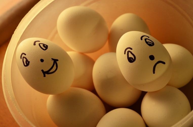 Photo of bowl of eggs, with one happy face and one sad face drawn with a Sharpie.