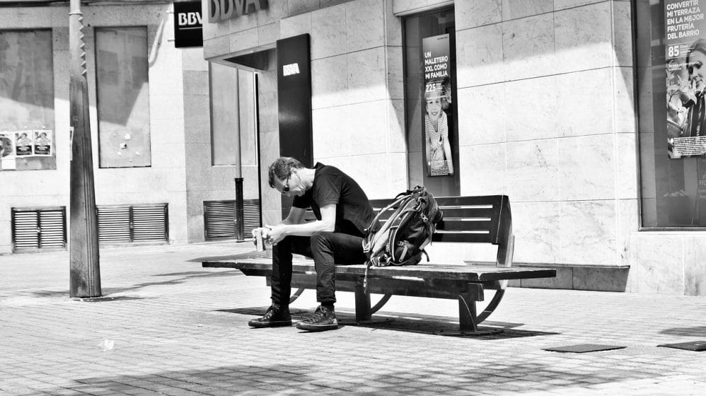 black and white photo of a man sitting on a bench