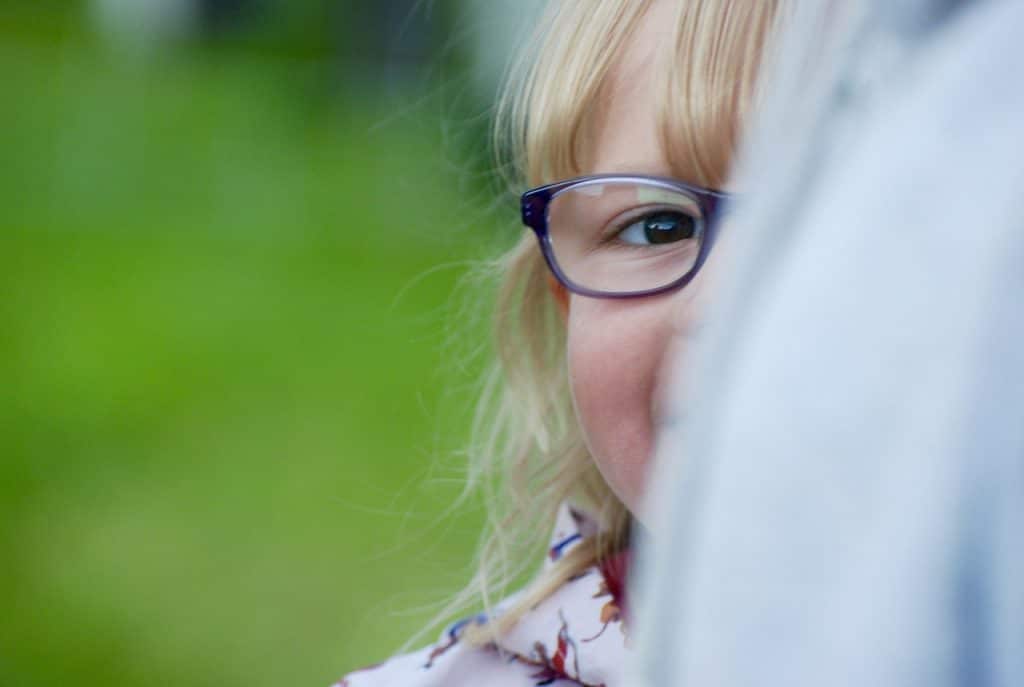 close-up photo of a shy girl peaking as she tries to hide