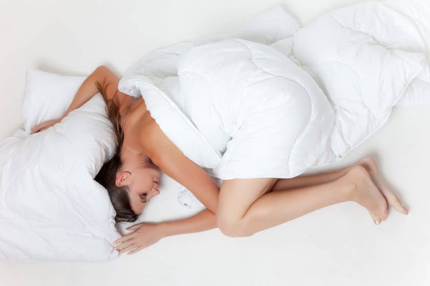 Sleeping woman at the best body pillow and she is covered by a white bed sheet